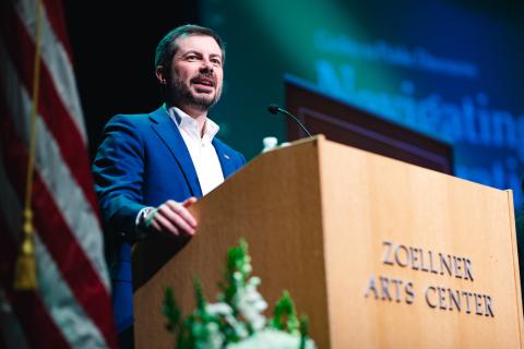 Pete Buttigieg stands at a podium with Zoellner Arts Center on the front of the podium.